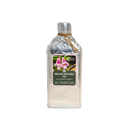 Melnā sezama eļļa 250ml stikla pudelē, kas ietīta sudraba folijā ar džutas auklu, uz balta fona. Uz etiķetes redzami purpura ziedi un teksts "MELNĀ SEZAMA eļļa" un "МАСЛО ЧЕРНОГО КУНЖУТА".